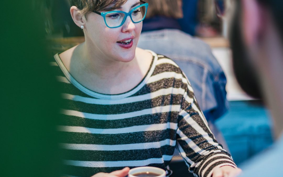 Image of Sarah discussing with a friend over coffee.
