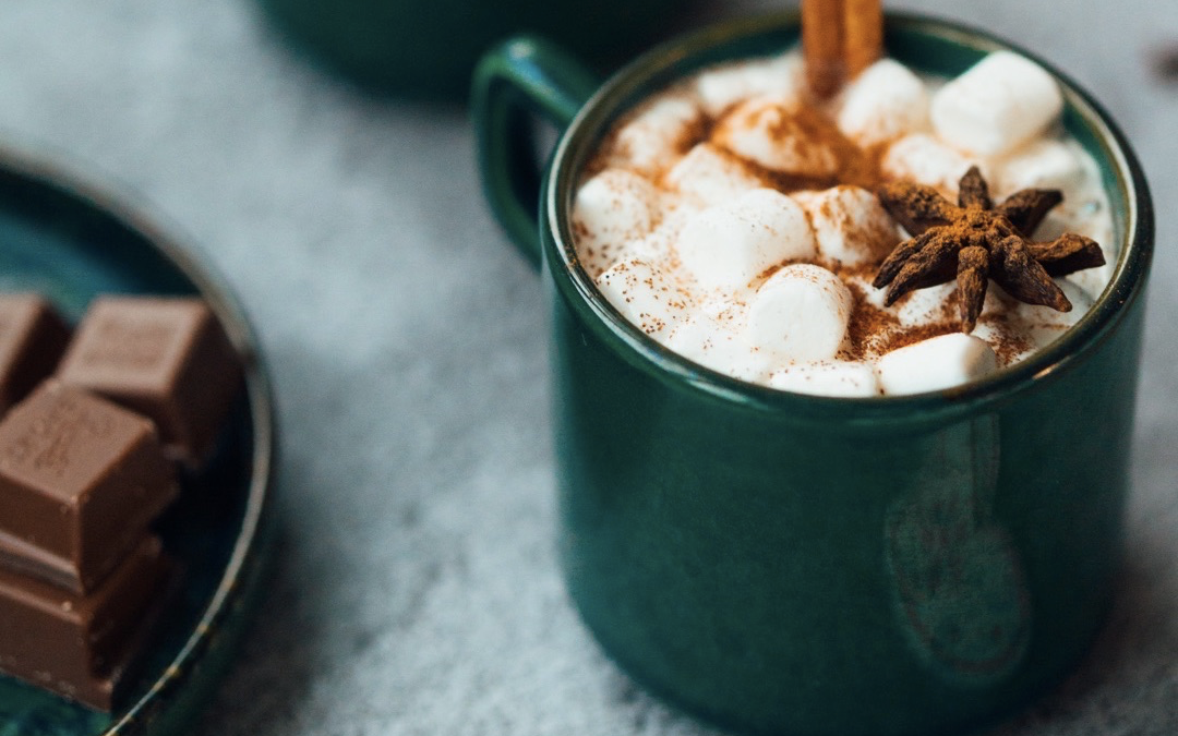 Image of hot cocoa in a teal mug with a cinnamon stick