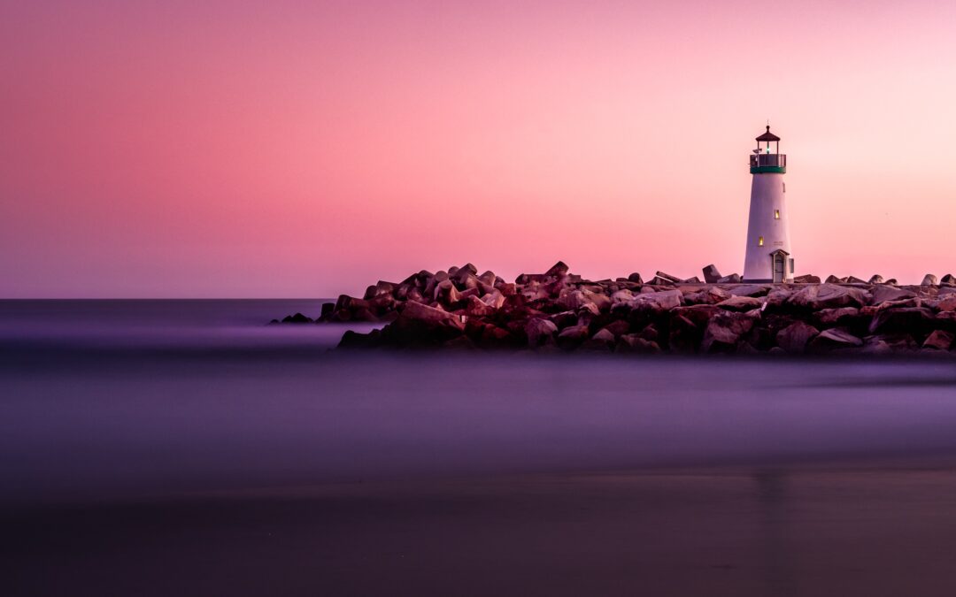 Image of a lighthouse against a pink sunrise/sunset