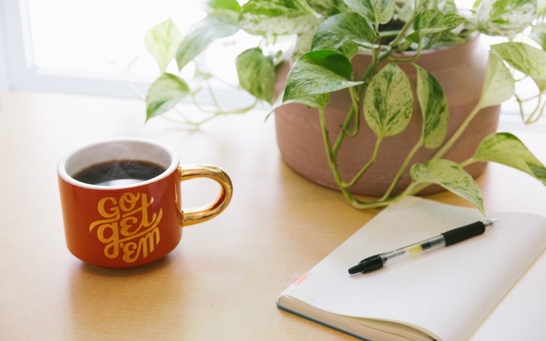 Image of a journal, a cup of coffee, and a plant